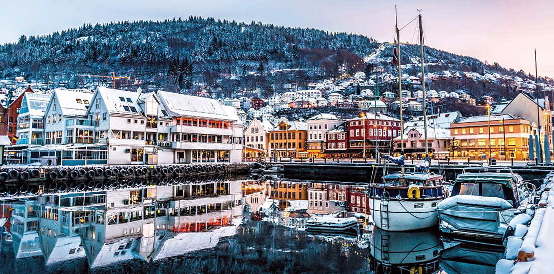 Bergen waterfront covered in snow at dusk, Norway